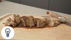 sliced meat on cutting board with utensils and lightbulber next to it