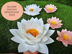 paper flowers sitting on top of grass next to a person's hand