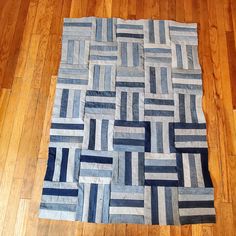 a blue and white rug on the floor with wooden floors in front of it that is made out of strips of fabric