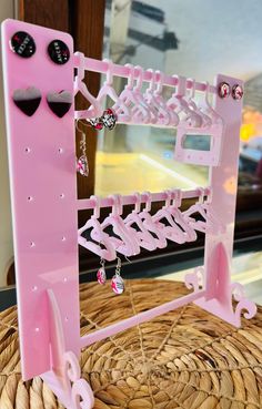 a pink plastic rack with earrings hanging from it's sides on top of a wicker basket