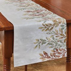 a wooden table topped with a white and brown table runner next to a wood table