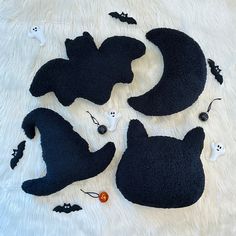 four black cat shaped rugs laying on top of a white fur covered bed with halloween decorations