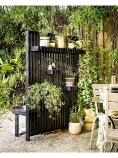 an outdoor garden with potted plants on the wall and table in the foreground