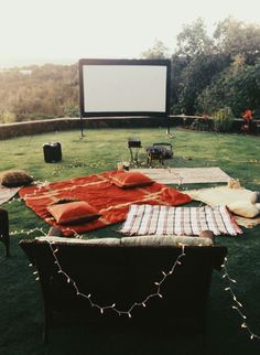 an outdoor movie is set up on the grass in front of a screen and chairs