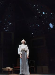 a woman standing on top of a stage in front of a black background with stars