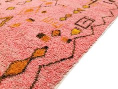 a pink rug with an orange and yellow design on the bottom is shown in full view