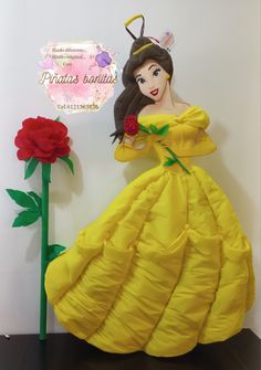 a paper mache of a woman in a yellow dress next to a red rose