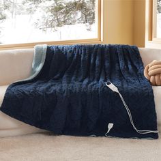 a blue blanket sitting on top of a white couch next to a window with snow outside