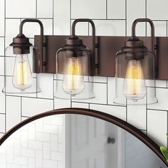 three lights on a wall above a mirror in a room with white tiles and tile walls