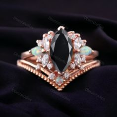 a black diamond and opal ring on top of a black cloth with white stones