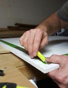 a man is working on some wood with a pair of scissors and a piece of paper