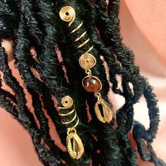 From the 'For The Goddess In You' Collection👑 Handcrafted with intention✨ Made with the best tarnish resistant wire, tigers eye bead and gold cowrie shell charm Adorns any medium sized locs, braids, and twists sized 7-9mm. Wire is 18g thickness- Firm but adjustable To get the most out of your jewelry take off your cuff before washing your hair 💦 *I do not accept returns but please don't hesitate to contact if there are any issues and I'd be more than happy to help💕 Peace & Love -Liz🤎 Locs With Gold Cuffs, Gold Braid Accessories, Faux Locs With Shells, Gold Hair Jewelry For Braids, Locs With Gold Accessories, Loc Charms Dreadlock Accessories, Hair Charms For Locs, Locs Jewelry Accessories, Braids With Gold Cuffs