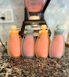 four baby bottles sitting on top of a counter next to a blender