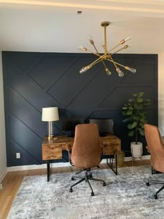 a room with two chairs and a desk in front of a wall that is painted black