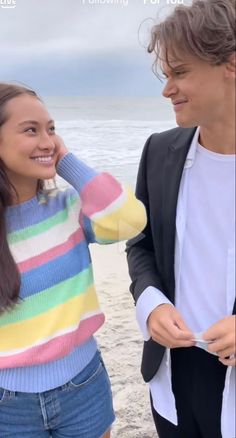 a man standing next to a woman on top of a beach