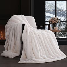 a white blanket sitting on top of a chair next to a fireplace