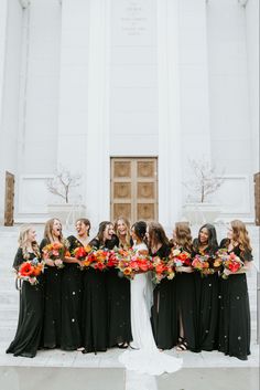 a group of women standing next to each other in front of a building with flowers