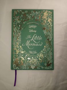 the little mermaid book is laying on a bed