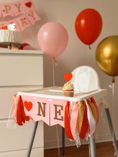 a table topped with a cupcake next to balloons