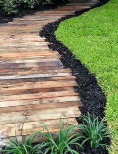 a wooden walkway in the middle of some grass