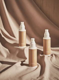 three spray bottles sitting on top of a bed next to a tan sheet with the word hello written on it