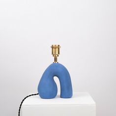 a blue object sitting on top of a white block next to a light fixture with a black cord