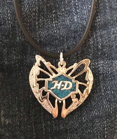 This silver Harley Davidson butterfly pendant is inlaid with turquoise and has the HD in silver on the front.    It also has the HD trademark on the back and pendant is approximately 1" high by 1&1/4" wide and is on a 4mm rubber cord, with the cord being about 16 - 18" and having a sterling silver clasp, better cord for those with metal allergies.  There is a 4" length of chain added to make it adjustable to individual taste The end of the cord by the clasp is small enough for you to add other b Silver Stamped Heart Pendant Jewelry, Silver Engraved Butterfly Jewelry, Silver Jewelry With Butterfly Charm For Anniversary, Turquoise Butterfly Sterling Silver Jewelry, Silver Heart Jewelry With Butterfly Charm, Silver Butterfly Jewelry For Collectors, Blue Stamped Jewelry For Gifts, Blue Stamped Jewelry For Gift, Turquoise Butterfly Charm Jewelry Gift