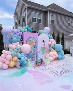 an outdoor birthday party with balloons and mermaid decorations on the top of a large table