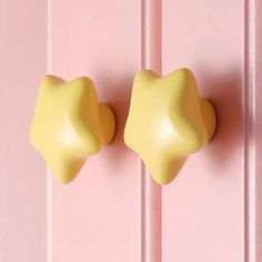 two yellow door knobs are on the pink wall and one is in the shape of a star