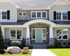 a large house with stone and shingles on the front door, windows, and landscaping