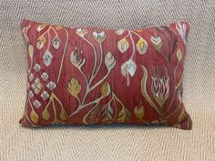 a red and gold decorative pillow on a couch