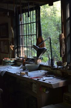 a woman sitting at a table in front of a window with tools on the counter