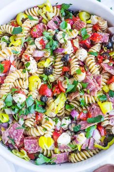 a pasta salad in a white bowl on top of a table