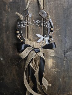 a welcome sign hanging on the side of a wooden door with black ribbon and flowers