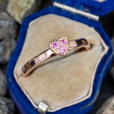 This gorgeous pink sapphire heart ring is centered with a heart that is set with three round cut pink sapphires. The ring is crafted of 14k rose gold and is currently a size 9. Pink 14k Gold Heart Ring Gift, Pink 14k Gold Heart Promise Ring, Pink 14k Gold Heart Ring For Promise, Valentine's Day Pink Gold Heart Cut Ring, Pink Gold Heart Cut Ring For Anniversary, Rose Gold Pink Sapphire Birthstone Promise Ring, Pink Gold Heart Ring For Valentine's Day Anniversary, Valentine's Day Anniversary Pink Gold Heart Ring, Pink Heart Cut Ruby Ring For Valentine's Day