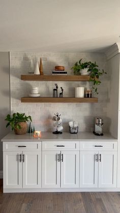 a kitchen with white cabinets and shelves filled with potted plants on top of them