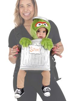 a woman holding a baby dressed as kermie from the muppets costume