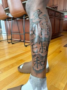 a man's leg with chinese writing on it in the middle of a kitchen