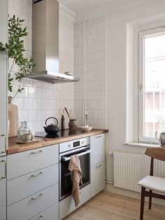 a kitchen with white walls and wooden floors has a potted plant on the counter