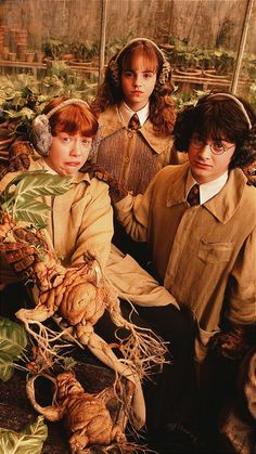 there are three people dressed in period clothing and holding some plant life, with one person sitting on the ground next to them