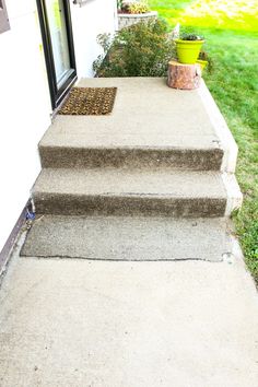 concrete steps lead up to the front door of a house with grass in the background