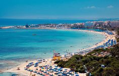 the beach is crowded with people and blue umbrellas