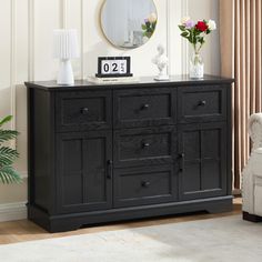 a black dresser with flowers and a clock on it's sideboard in a living room