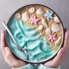 a person holding a plate with sand and sea shells on it