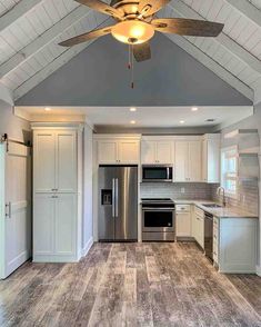 an empty kitchen with a ceiling fan and white cabinets