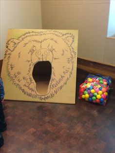 a cardboard box with a bear's head cut out on the inside and balls in the outside