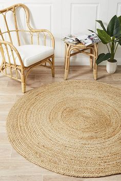 a large round rug in the middle of a room with chairs and a potted plant