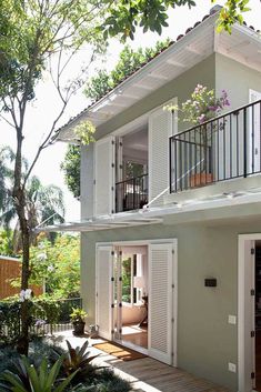 a house with white shutters on the front and side doors open to let in light