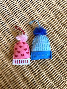 two small knitted hats sitting on top of a wicker table next to each other