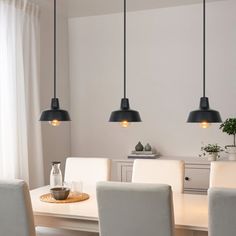 a dining room table with four lights hanging over it